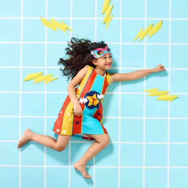 a girl flying in the air, wearing a personalised super hero dress