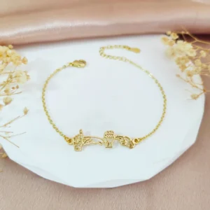 A gold coloured braclet that has gold asl hand signs on it. The handsigns read as a name