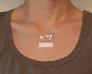 a metal necklace worn on a woman. The necklace has a word written in asl sign language, the word on this necklace is 'love'