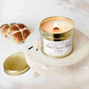 a candle in a metal tin, next to a hot cross bun